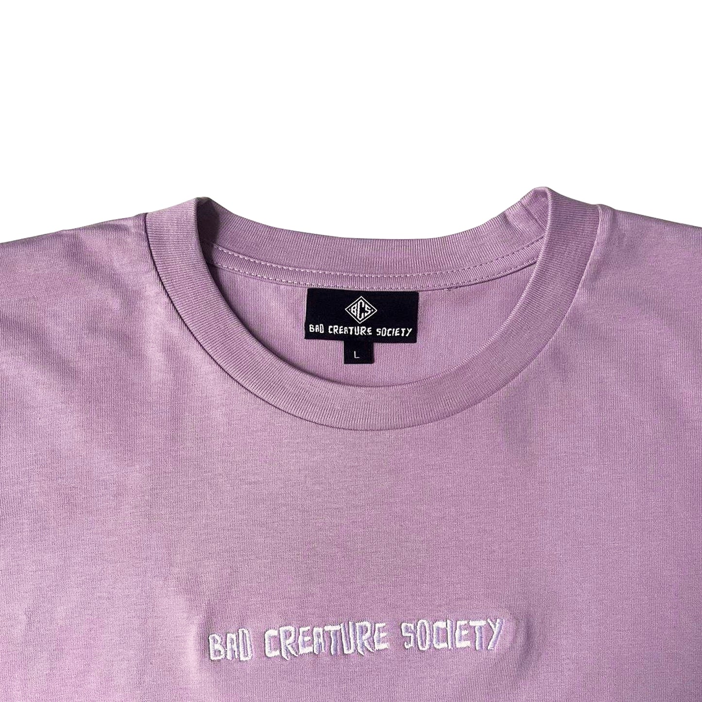 Lilac t-shirt with 'Bad Creature Society' text and brand label on a white background